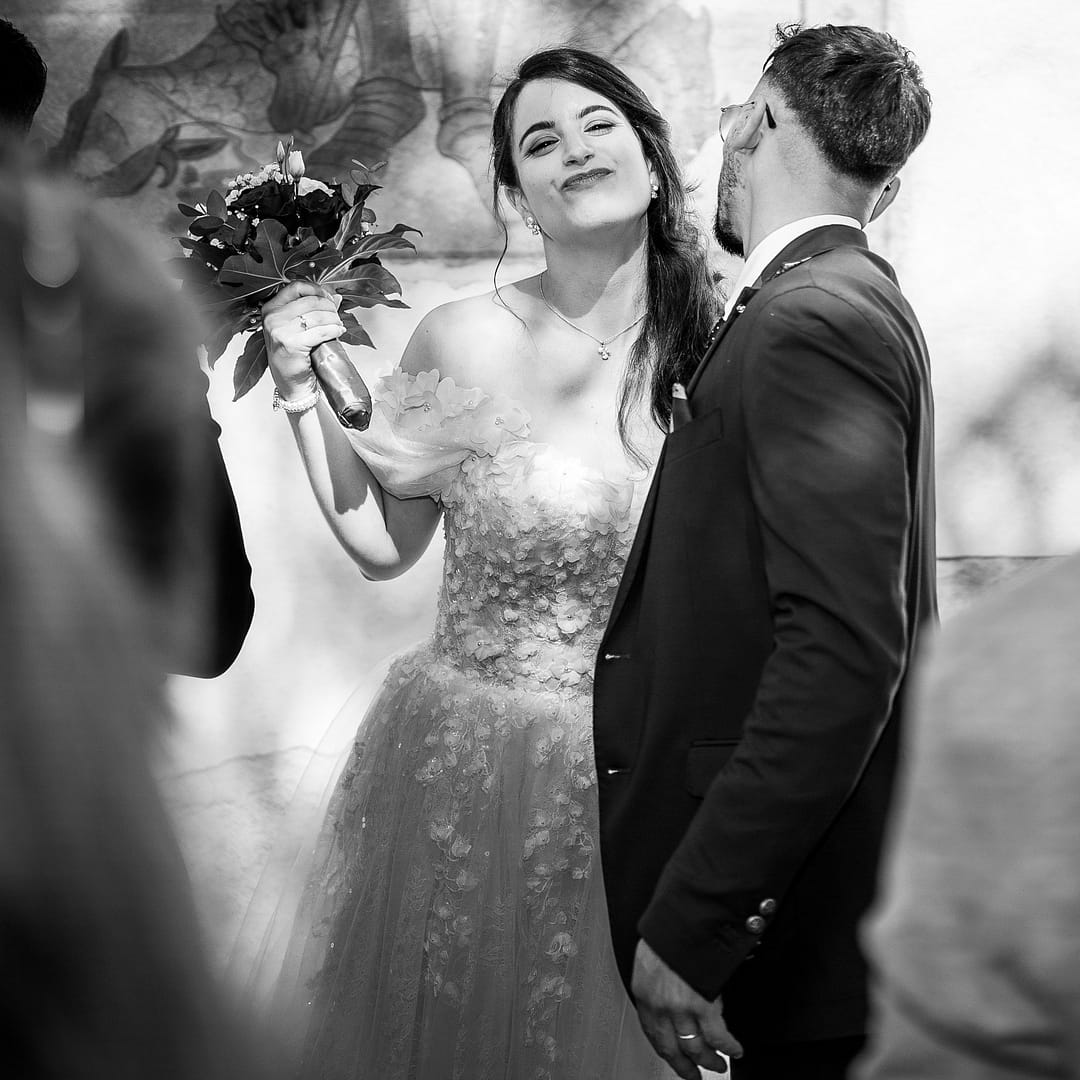 Mariée en noir et blanc embrassant ses proches à la sortie de l’église – moment spontané capturé par Erick Del Cucina, photographe de mariage en Suisse