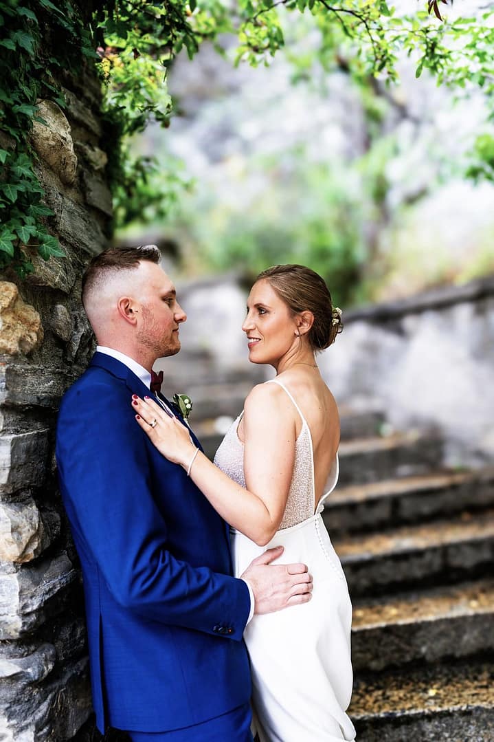 Photographie de mariage romantique dans les ruelles de Sion. Mariés posant près d'un escalier de pierre dans le quartier historique sédunois, ambiance authentique et intemporelle en Valais.