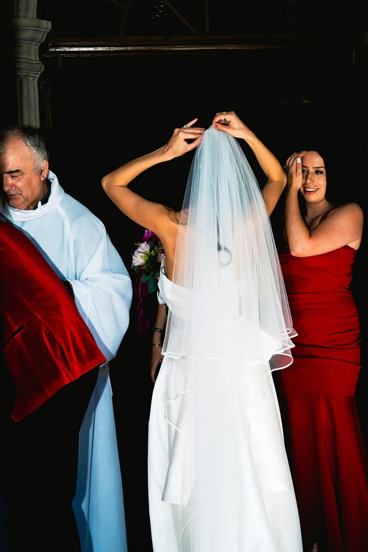 Mariée ajustant son voile de dos devant une église à Genève, photo de mariage élégante et naturelle